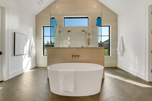 full bath with lofted ceiling, a soaking tub, baseboards, and a walk in shower