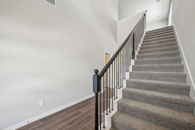 stairs with wood finished floors, visible vents, and baseboards