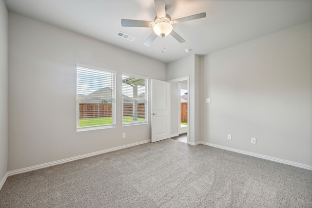 carpeted empty room featuring baseboards, a ceiling fan, and visible vents