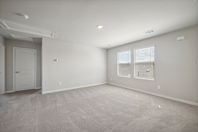 carpeted empty room featuring attic access, baseboards, and visible vents