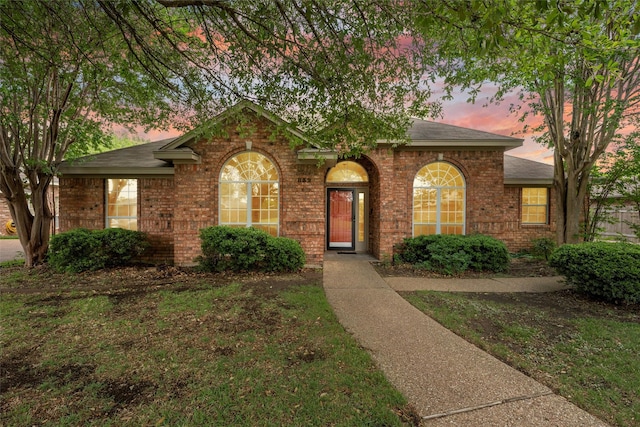 view of front of home with brick siding and roof with shingles