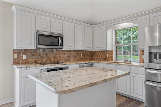 kitchen featuring light stone counters, wood finished floors, stainless steel appliances, and a sink