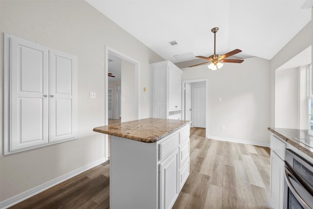 kitchen featuring light wood finished floors, white cabinets, stainless steel oven, vaulted ceiling, and a ceiling fan