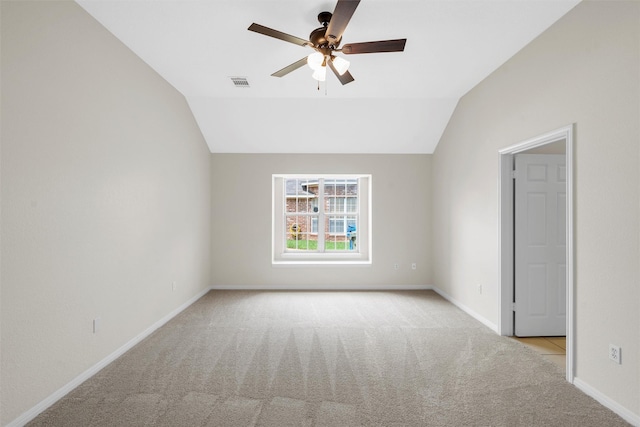 spare room featuring ceiling fan, baseboards, light colored carpet, lofted ceiling, and visible vents