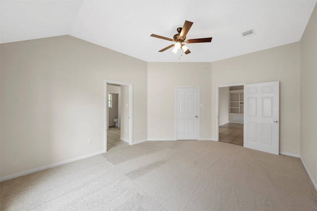 unfurnished bedroom with lofted ceiling, visible vents, light carpet, baseboards, and ensuite bathroom