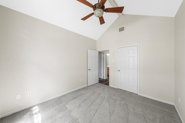 unfurnished bedroom featuring beamed ceiling, light carpet, baseboards, and high vaulted ceiling