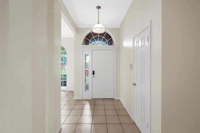 foyer entrance with baseboards, ornamental molding, and light tile patterned floors