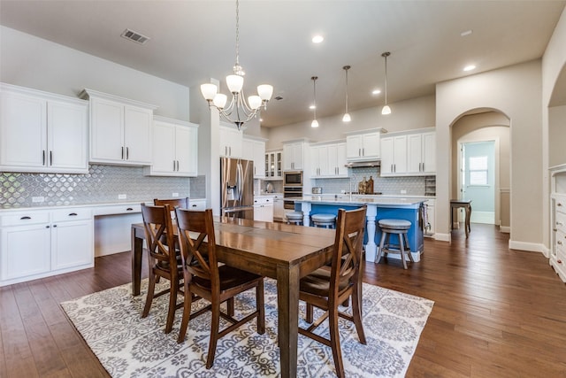560 Southwestern Dr, Rockwall, TX 75087 - dining space featuring a chandelier, dark wood-type flooring, arched walkways, recessed lighting, and baseboards