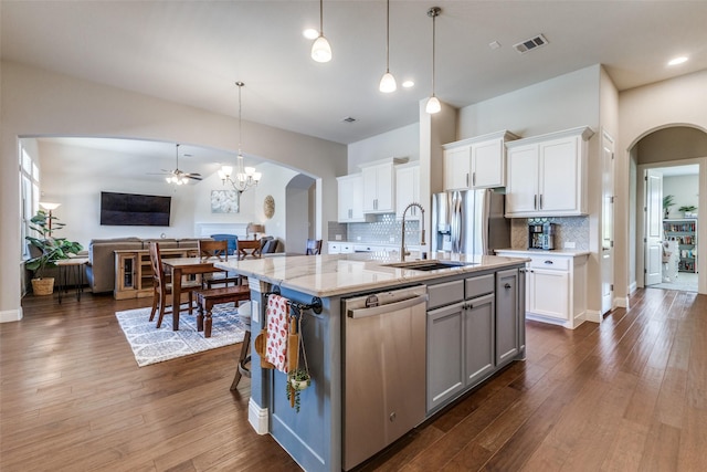 560 Southwestern Dr, Rockwall, TX 75087 - kitchen featuring stainless steel appliances, arched walkways, a sink, open floor plan, and white cabinets