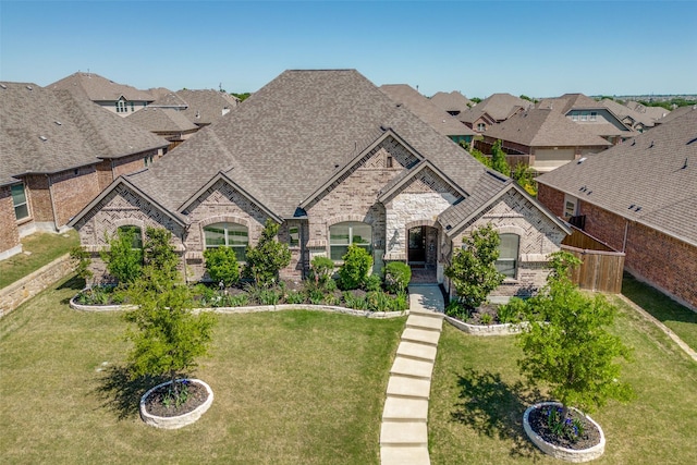 560 Southwestern Dr, Rockwall, TX 75087 - french country style house with a front yard, a shingled roof, stone siding, and a residential view