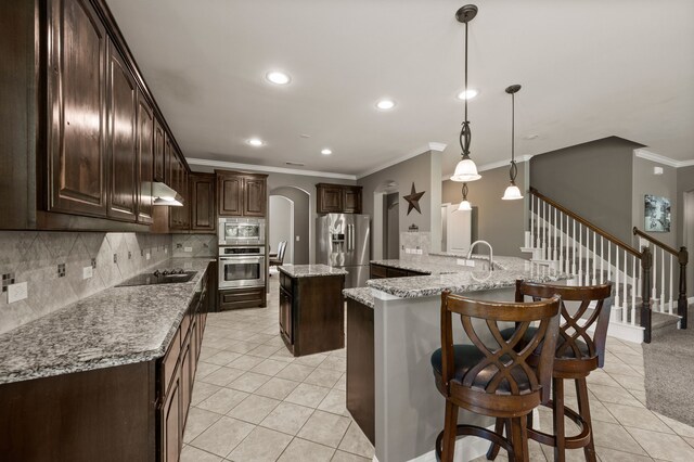 kitchen featuring ornamental molding, appliances with stainless steel finishes, a center island, and light tile patterned flooring