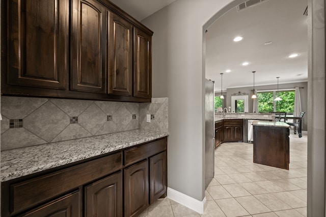 kitchen with dark brown cabinets, a sink, arched walkways, a peninsula, and tasteful backsplash