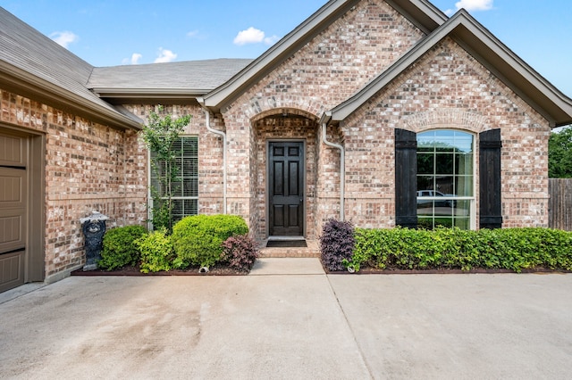 view of exterior entry with brick siding and a patio area
