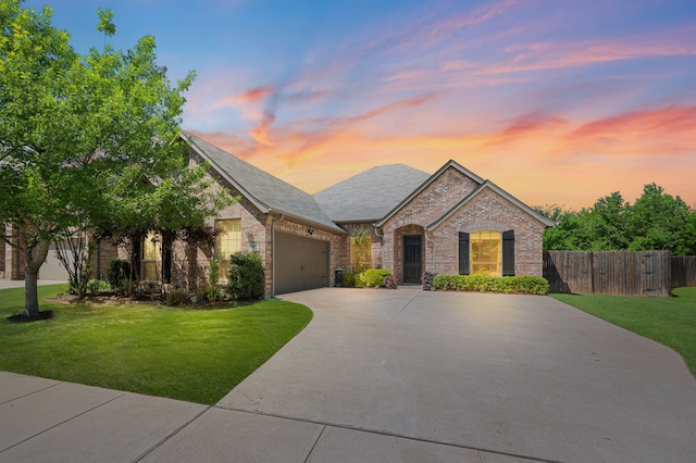 french country style house featuring concrete driveway, an attached garage, brick siding, and a lawn