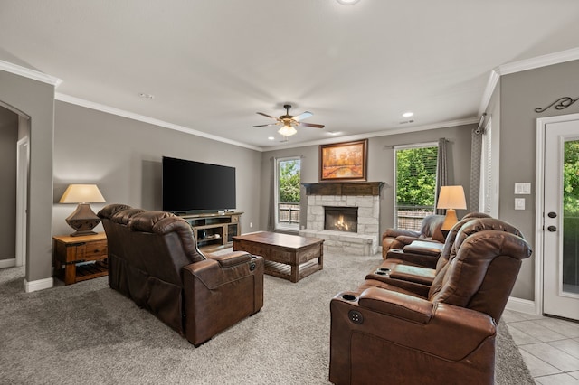 living room with ceiling fan, baseboards, ornamental molding, and a stone fireplace