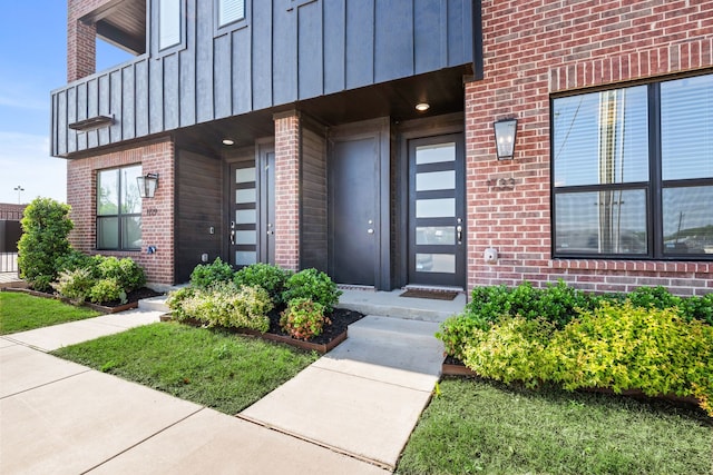 property entrance featuring brick siding, board and batten siding, and a balcony
