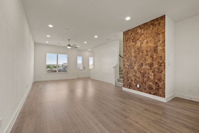 spare room with baseboards, recessed lighting, wood finished floors, ceiling fan, and stairway