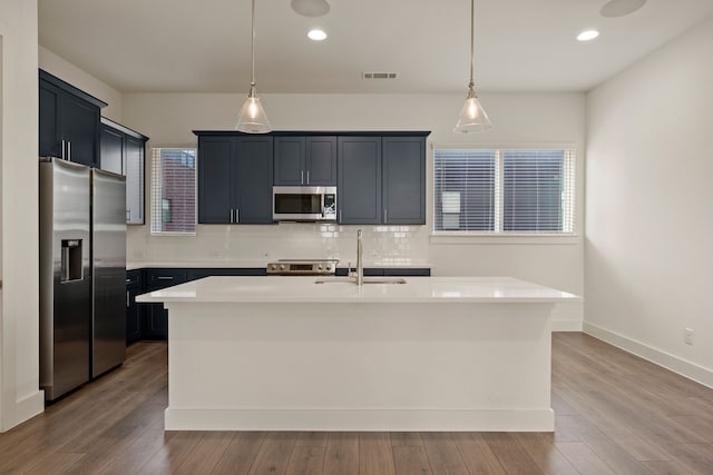 kitchen featuring tasteful backsplash, a sink, stainless steel appliances, light countertops, and decorative light fixtures