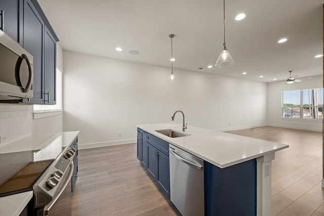 kitchen featuring stainless steel appliances, a ceiling fan, a sink, light wood-style floors, and blue cabinetry