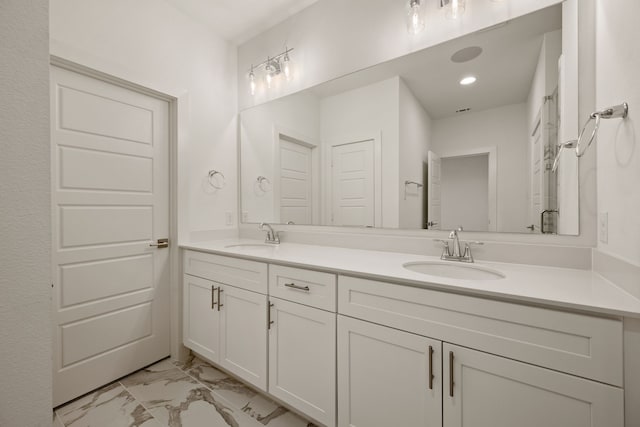 bathroom with double vanity, marble finish floor, and a sink