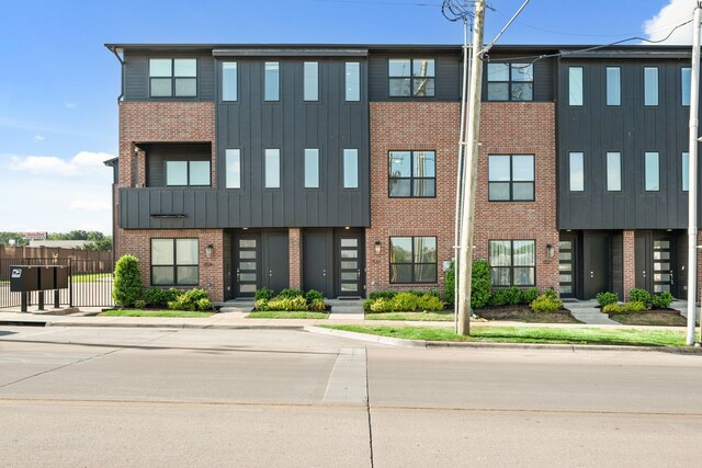 view of front facade with fence, brick siding, and board and batten siding
