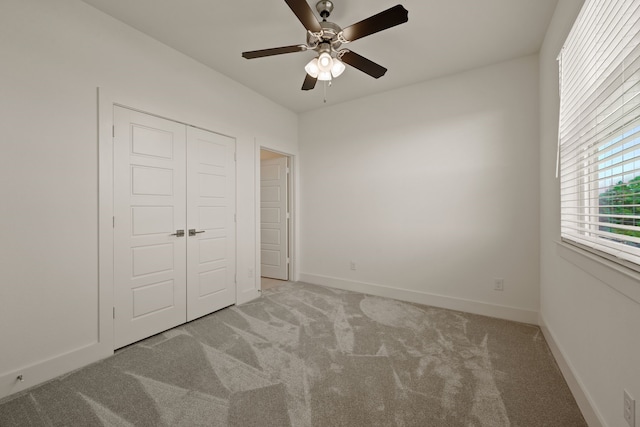 unfurnished bedroom with baseboards, a closet, a ceiling fan, and light colored carpet