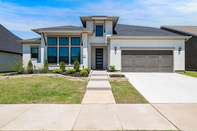 prairie-style home with a shingled roof, an attached garage, stucco siding, a front yard, and driveway