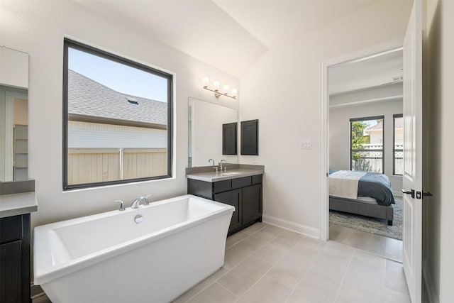 ensuite bathroom featuring tile patterned flooring, ensuite bath, vanity, a freestanding tub, and baseboards