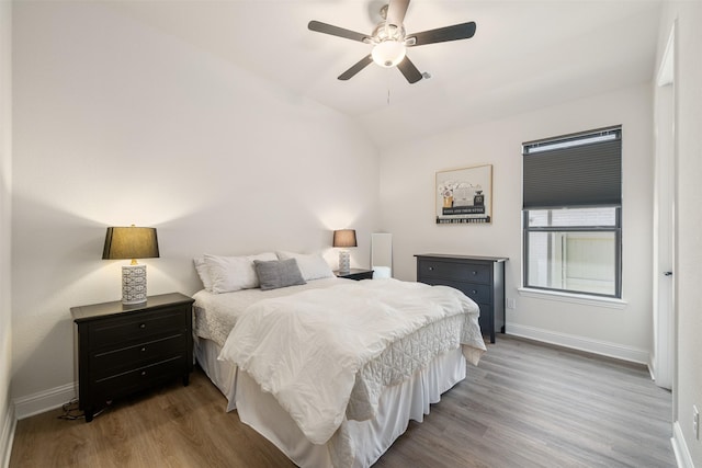 bedroom with baseboards, ceiling fan, vaulted ceiling, and wood finished floors