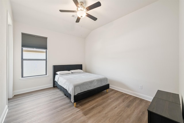 bedroom featuring baseboards, a ceiling fan, lofted ceiling, and light wood-type flooring