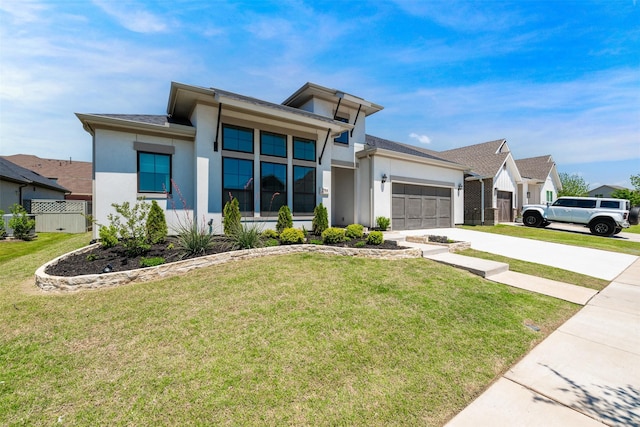 prairie-style house featuring a garage, fence, a front lawn, concrete driveway, and stucco siding