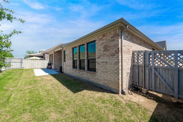 back of house featuring fence, a patio, brick siding, a gate, and a yard