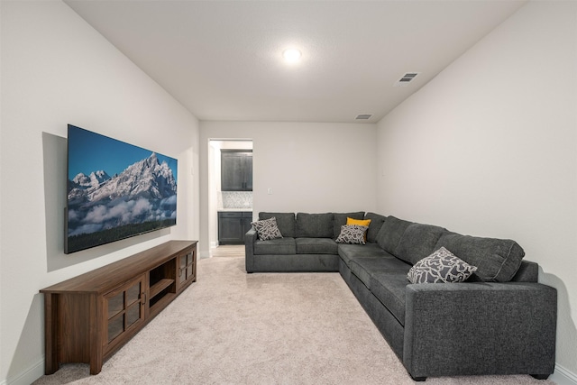 living area with baseboards, light carpet, and visible vents