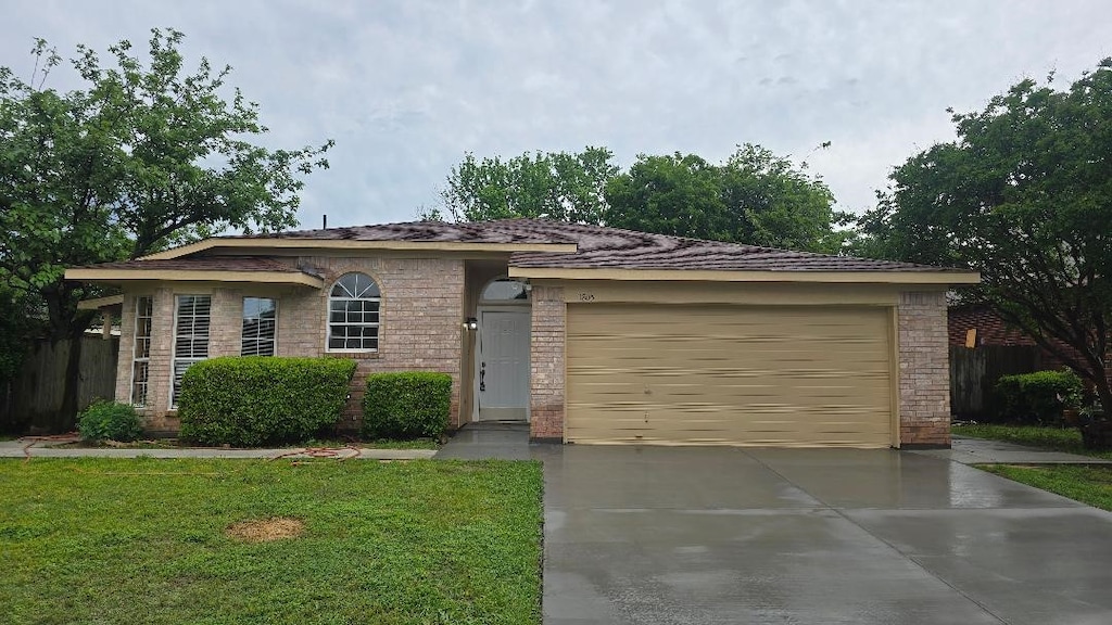 single story home with driveway, a front yard, fence, brick siding, and a garage