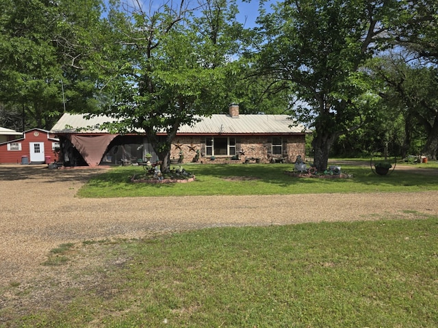 single story home with a chimney, a front yard, and metal roof