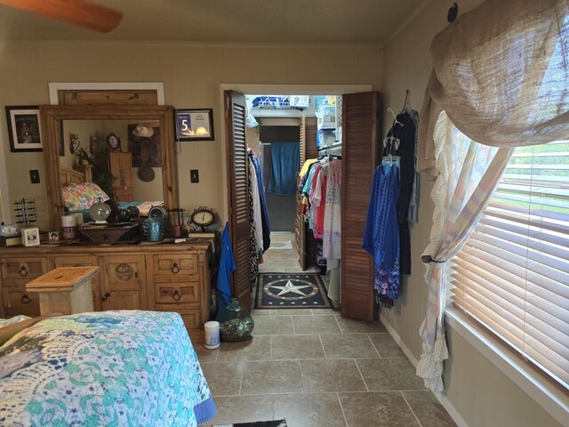 bedroom featuring a walk in closet, a closet, crown molding, and baseboards