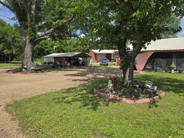 view of front of home featuring a detached carport, a front lawn, driveway, and metal roof