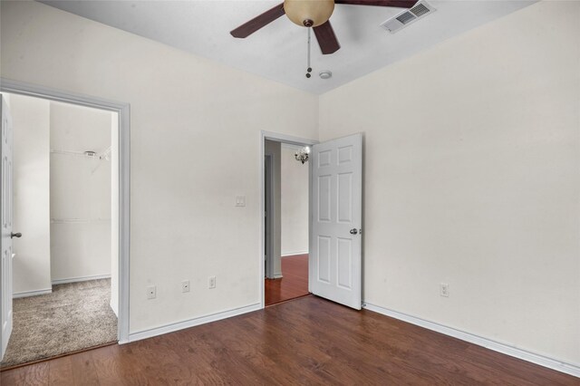 unfurnished bedroom featuring wood finished floors, visible vents, a closet, baseboards, and ceiling fan