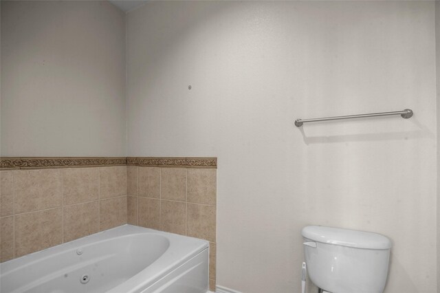bathroom with a whirlpool tub and toilet