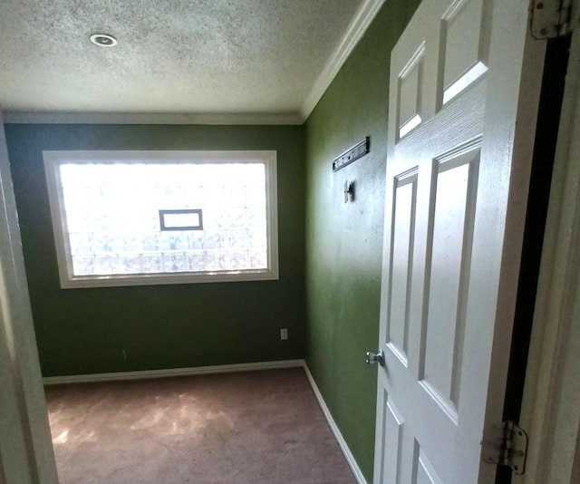 unfurnished room with baseboards, carpet flooring, a textured ceiling, and crown molding