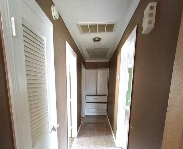 corridor featuring baseboards, visible vents, and light tile patterned floors