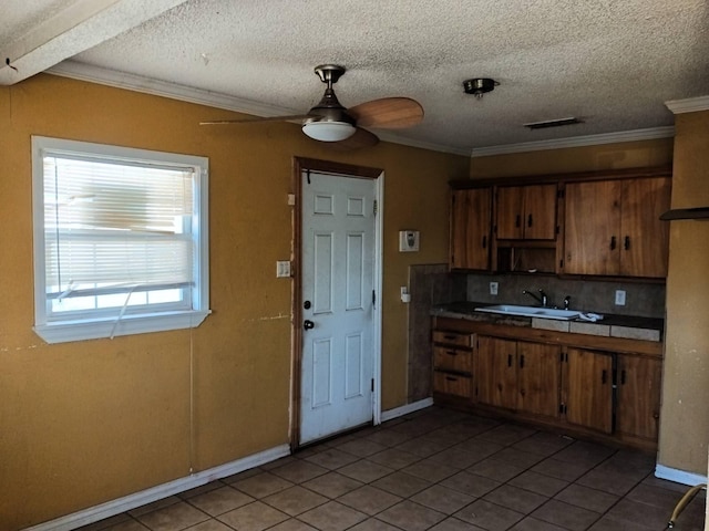 kitchen with light tile patterned floors, a sink, crown molding, brown cabinetry, and ceiling fan