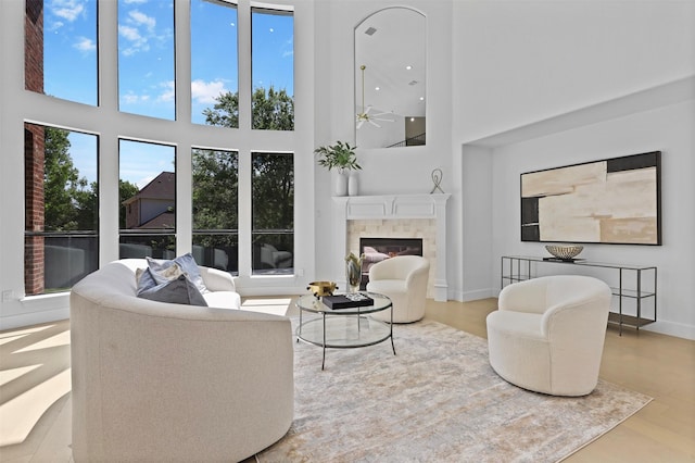 1750 Greenwood Ct, Prosper, TX 75078 - living area with baseboards, a glass covered fireplace, a ceiling fan, wood finished floors, and a high ceiling