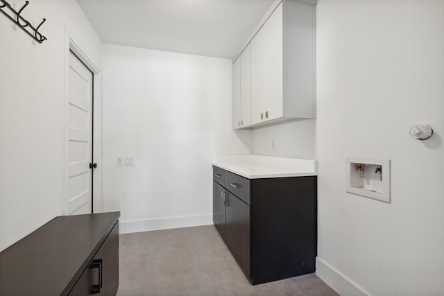 washroom featuring hookup for a washing machine, baseboards, and cabinet space