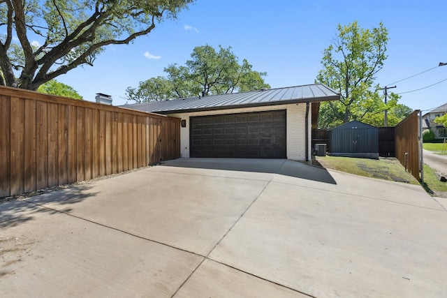 garage with fence, driveway, and central AC