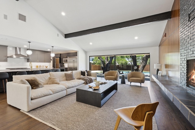 living room with recessed lighting, beamed ceiling, a brick fireplace, visible vents, and dark wood-type flooring