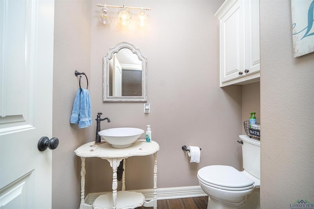 225 Clements Cir, Tatum, TX 75691 - bathroom featuring wood finished floors, toilet, baseboards, and a sink