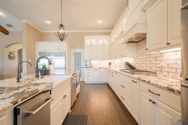 225 Clements Cir, Tatum, TX 75691 - kitchen with backsplash, appliances with stainless steel finishes, custom exhaust hood, and light stone counters