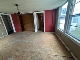 unfurnished bedroom featuring baseboards and a notable chandelier