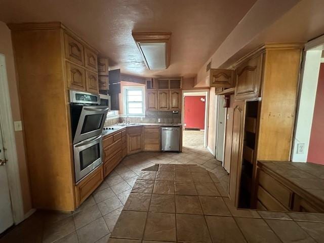 kitchen with tile counters, a sink, decorative backsplash, stainless steel appliances, and visible vents